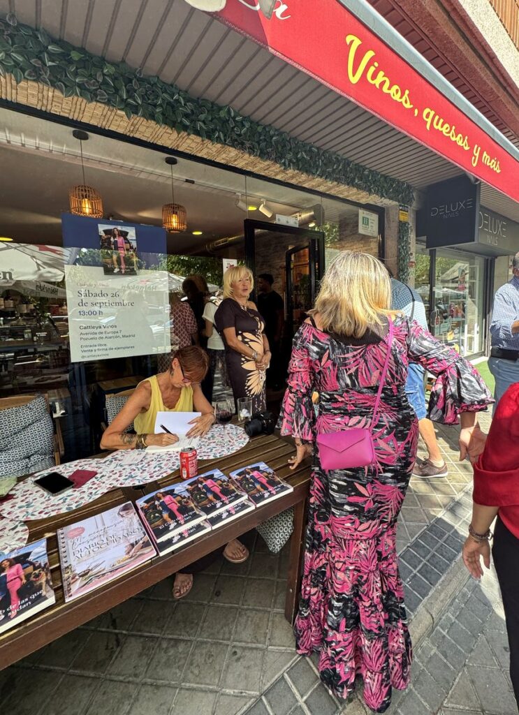 Invitados en la puerta de Cattleya Vinos mientras Helena Viñuelas firma ejemplares en la mesa de la terraza