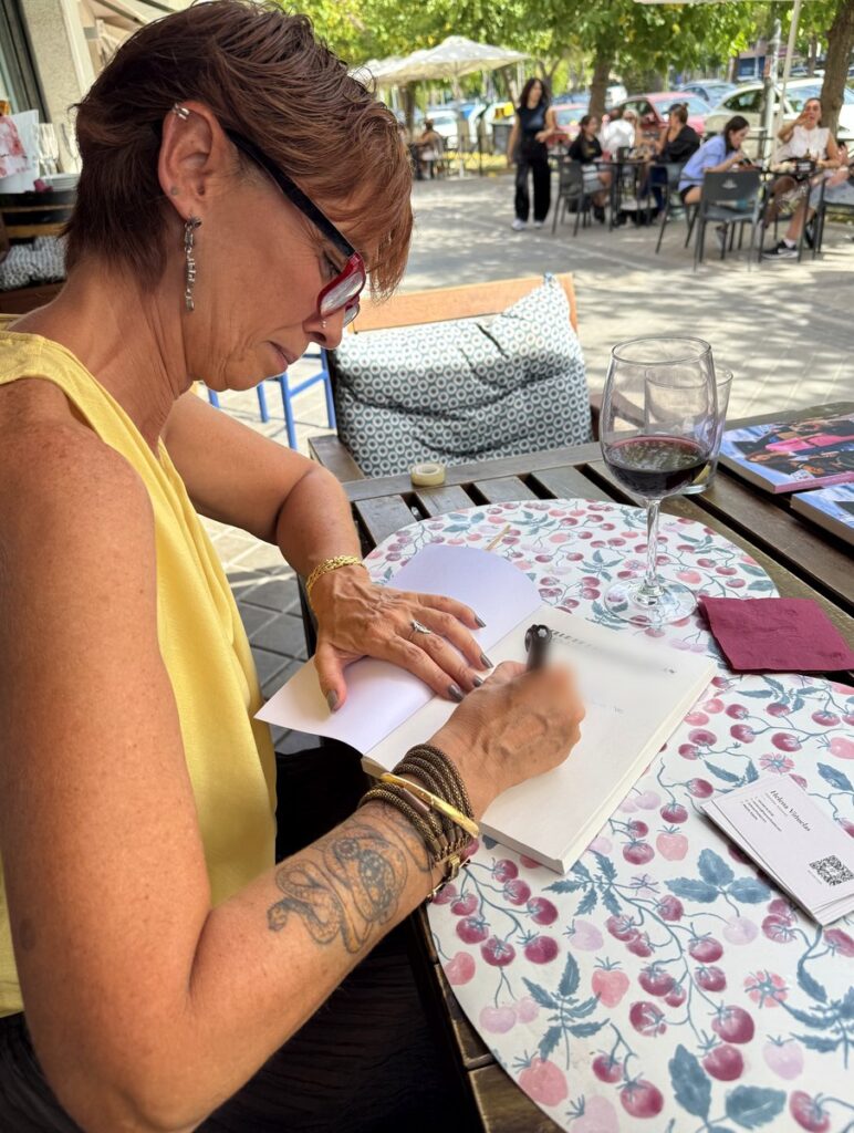 Helena Viñuelas escribe una dedicatoria en un ejemplar de su novela, sentada en la terraza