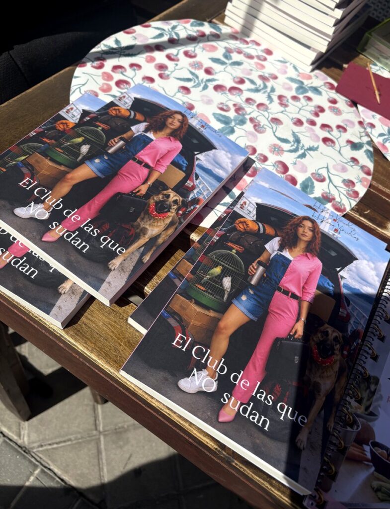 Ejemplares de «El club de las que NO sudan» firmados sobre la mesa de la terraza, con la pila de libros detrás